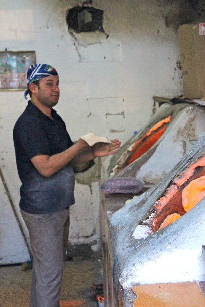 How to make naan: flatten bread into a disc, then stick it on the side of the half-dome ovens until cooked.